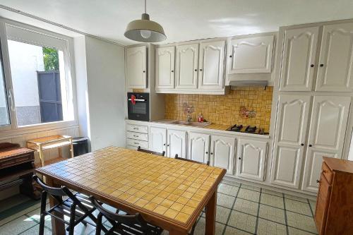 une cuisine avec des armoires blanches et une table en bois dans l'établissement Maison indépendante proche Paris Saclay, Massy, à La Ville-du-Bois