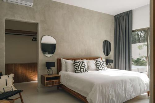 a bedroom with a large white bed and a mirror at Large 6BR Tulum Villa with Pool Aldea Zama in Tulum