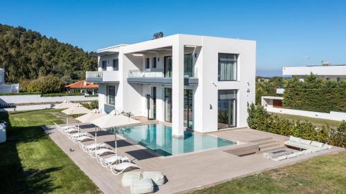 a large white house with a swimming pool and lounge chairs at Armonia Luxury Villa in Triánta