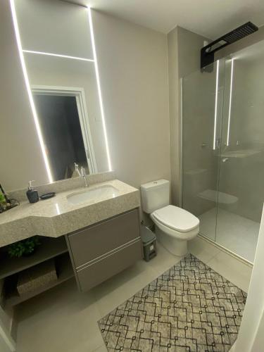 a bathroom with a toilet and a sink and a shower at Apartamento Sunset Residence in Dourados