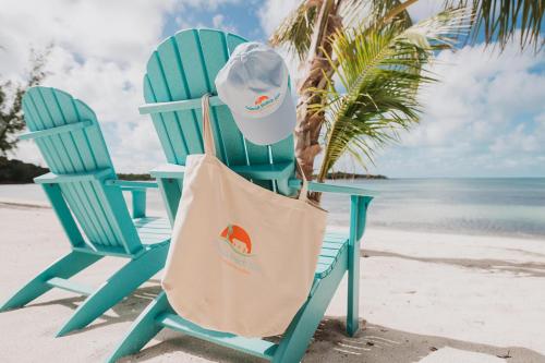 a blue chair with a hat and a bag on a beach at Guana Beach Inn in Great Guana Cay