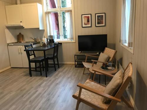 a living room with a table and chairs and a kitchen at Tollgaarden Gjestegaard in Larvik
