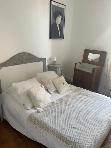 a bed with white sheets and pillows in a bedroom at Il était une fois un jardin in Saint-Fargeau