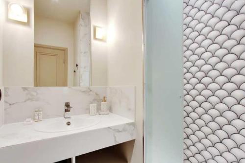 une salle de bain avec un lavabo et un miroir dans l'établissement V Vast Apartment, Steps from Place des Vosges AC, à Paris
