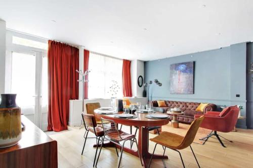 un salon avec une table, des chaises et un canapé dans l'établissement V Vast Apartment, Steps from Place des Vosges AC, à Paris