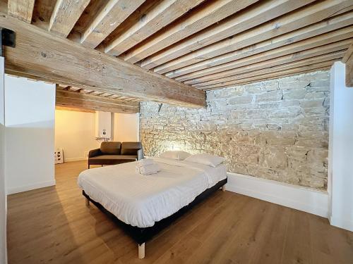 une chambre avec un lit et un mur en pierre dans l'établissement My home, Belfort 2 bis, à Lyon