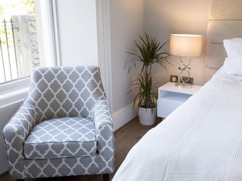 a bedroom with a bed and a chair next to a window at The Lane Hotel in Edinburgh