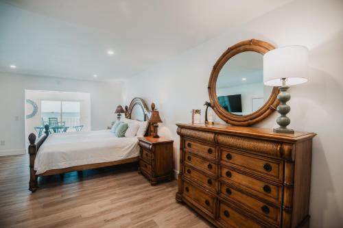 a bedroom with a bed and a dresser with a mirror at Guana Beach Inn in Great Guana Cay