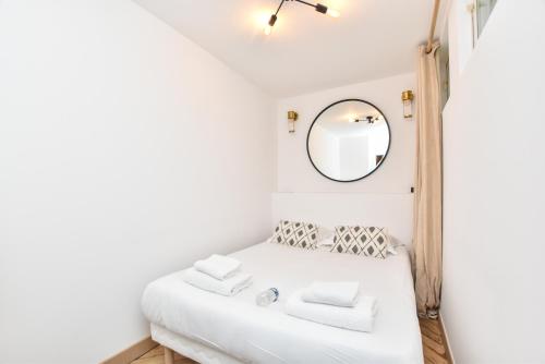 une chambre avec un lit blanc avec un miroir dans l'établissement Cosy apartment - 2BR-6P - Bastille, à Paris