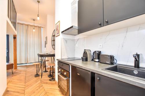 une cuisine avec un évier et un plan de travail dans l'établissement Cosy apartment - 2BR-6P - Bastille, à Paris