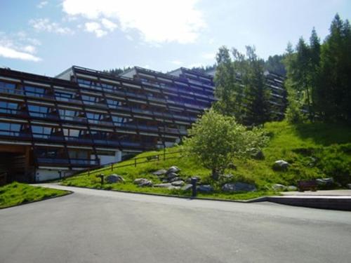 un grand bâtiment avec un jardin en face dans l'établissement Studio cosy pour 2 à Arc 1600, ski aux pieds, proche commerces et remontées mécaniques - FR-1-411-446, à Arc 1600