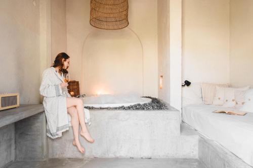 a woman sitting in a bath tub in a bathroom at GAIA Alaçatı Bazaar in Alacati