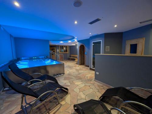 a large room with a swimming pool with blue lighting at Hotel Garni Arnica ***S in Madonna di Campiglio
