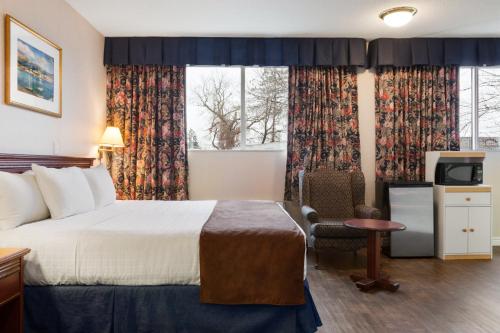 Habitación de hotel con cama y silla en Days Inn by Wyndham Brockville en Brockville