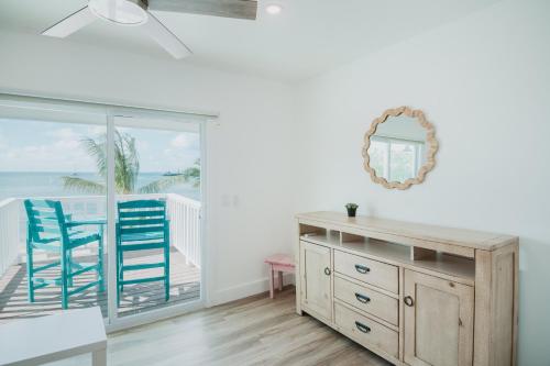 a room with two blue chairs and a dresser with a mirror at Guana Beach Inn in Great Guana Cay