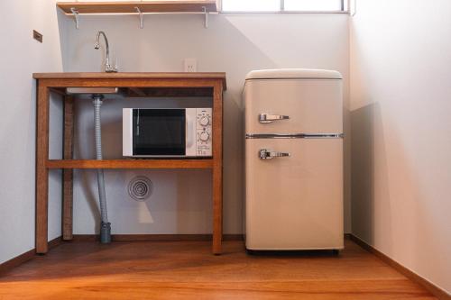 a kitchen with an old refrigerator next to a microwave at 港に停泊する町のフロント moyai 舫 in Choshi