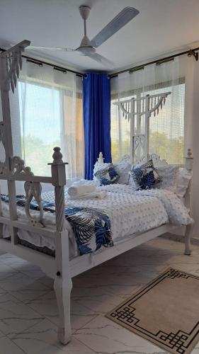 a white bed in a bedroom with blue curtains at Casa Marabella C2 in Ukunda