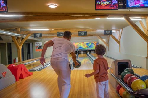 a man and a child playing a bowling alley at Rajska polana Domki PREMIUM ,na odludziu z prywatną BALIĄ z jacuzzi i sauną ,Cisza,rowery elektryczne,góry,astroprzygoda,- Adršpach, Skalne Miasto, Zamek Książ,Andrzejówka,Karpacz, Śnieżka,Janskie Laznie,Pec in Mieroszów