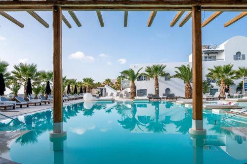 a pool at a resort with palm trees at Smy Mediterranean White Santorini in Kamari