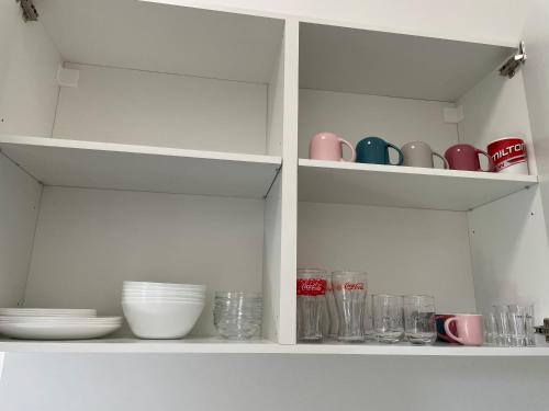 a white cabinet with cups and plates and bowls at Kiss Vendégház 2-3 in Kaposvár