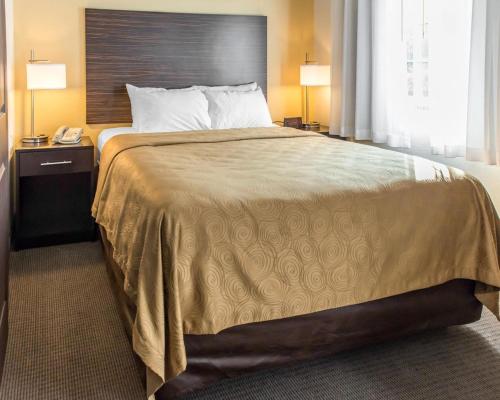 duże łóżko w pokoju hotelowym z 2 lampami w obiekcie MainStay Suites Pittsburgh Airport w mieście Imperial