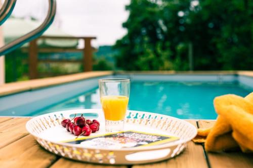 - un verre de jus d'orange et des fruits sur une table au bord de la piscine dans l'établissement Proche d'Agen - Location de vacances 6 personnes avec piscine privée à la campagne, à Colayrac-Saint-Cirq