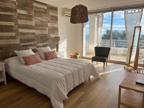 une chambre avec un grand lit et une chaise dans l'établissement Villa Margaux Prestige, à Sète
