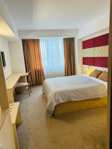 a hotel room with a large bed and a desk at Hotel Plaza in Craiova