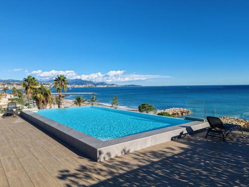 une piscine avec l'océan en arrière-plan dans l'établissement Pearl Beach - Rooftop Pool Seaside, à Villeneuve-Loubet