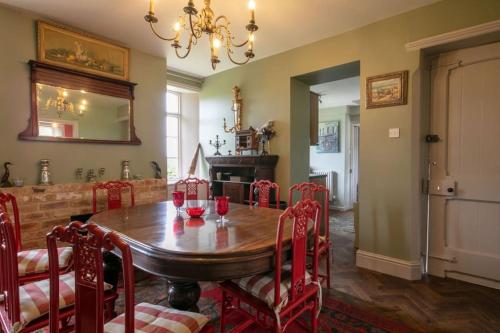 a dining room with a wooden table and red chairs at Beautiful Lodge Cottage near Belvoir Castle in Lincolnshire