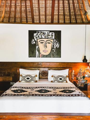 a bedroom with a bed with a painting of a woman at Villa Asrava Ubud in Ubud