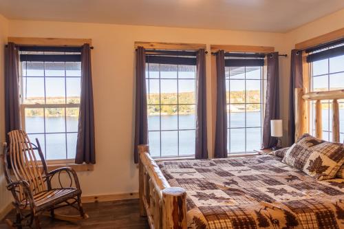 a bedroom with windows and a bed and a chair at Keweenaw Waters Resort in Houghton