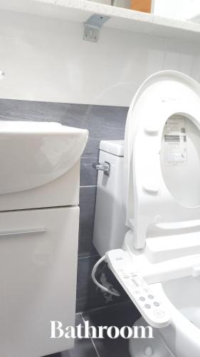 a bathroom with a white toilet and a sink at Sea Star Hostel in Yeosu