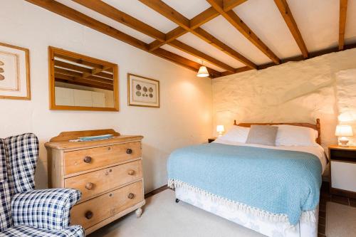 une chambre avec un lit, une commode et une chaise dans l'établissement Small Cottage, à Haverfordwest