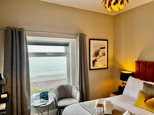 a bedroom with a bed and a window and a chair at Hotel No5, Beachfront with Free Private Car Park in Llandudno