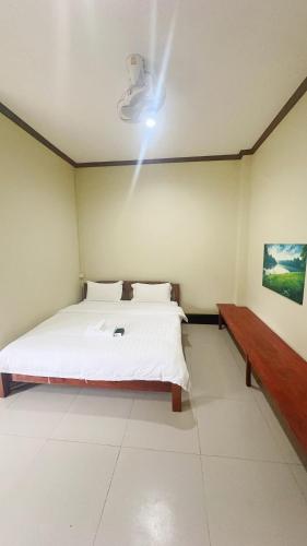 a bedroom with a white bed and a bench at Happy Hotel in Vang Vieng