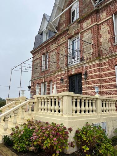 - un grand bâtiment en briques avec un balcon blanc dans l'établissement Le Manoir de La Baronnie, à Norrey-en-Auge