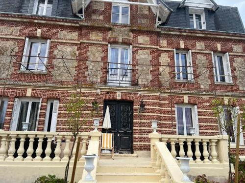 un bâtiment en briques rouges avec une porte noire dans l'établissement Le Manoir de La Baronnie, à Norrey-en-Auge