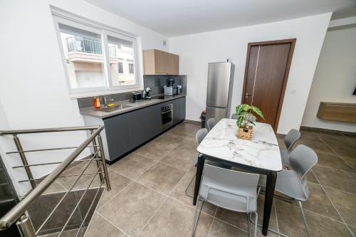 a kitchen with a table and a stainless steel refrigerator at Stylish Private Entrance Maisonette 2 Bed in St Paul's Bay
