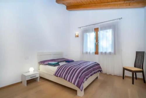 a bedroom with a bed and a chair and a window at Sun Villa in Càneva