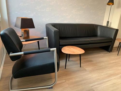 a living room with a black couch and a table at Hello Noordwijk - Familiehuis Quarles van Uffordstraat 77 in Noordwijk aan Zee