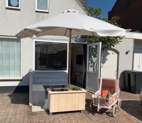an umbrella and a chair under a table at Hello Noordwijk - Familiehuis Quarles van Uffordstraat 77 in Noordwijk aan Zee