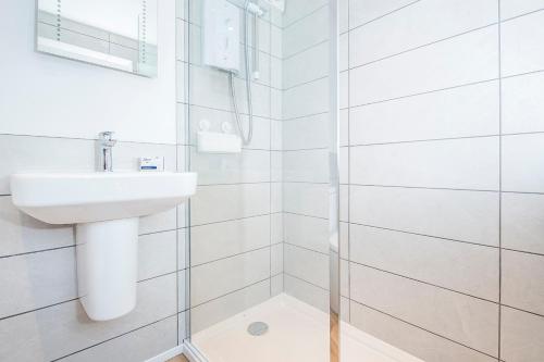 une salle de bain blanche avec lavabo et douche dans l'établissement Small Cottage, à Haverfordwest