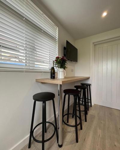 a kitchen with a bar with stools and a counter at Seiriol, Modern Lodge with Games Room Access in Menai Bridge