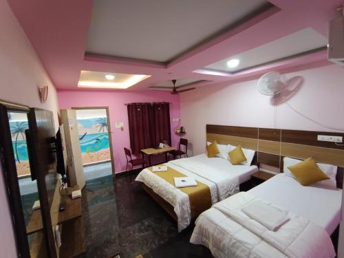 a hotel room with two beds and a couch at Sri Murugan Beach Paradise Hotel in Mahabalipuram
