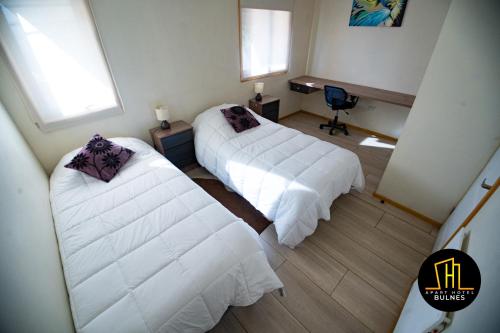 a bedroom with two beds and a desk with a chair at APART HOTEL EN BULNES in Bulnes