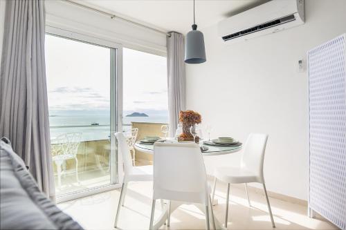 una sala da pranzo con tavolo e sedie e una grande finestra di Vista de Cinema Praia da Armação dos Búzios a Búzios