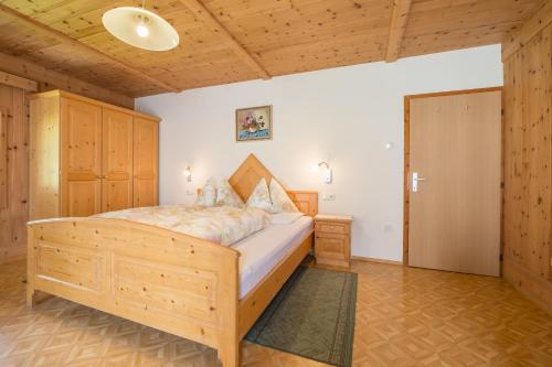 a bedroom with a large wooden bed and a door at Obermarhof Gsies in Prateria