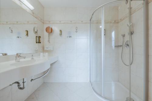 a white bathroom with a shower and a sink at KERSCHDORFER - wohlfühlhotel garni - adults only in Kaltenbach