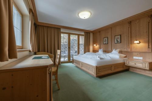 a bedroom with a large bed and a desk at KERSCHDORFER - wohlfühlhotel garni - adults only in Kaltenbach